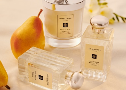 Colognes et bougies English Pear and Freesia sur une table avec une poire