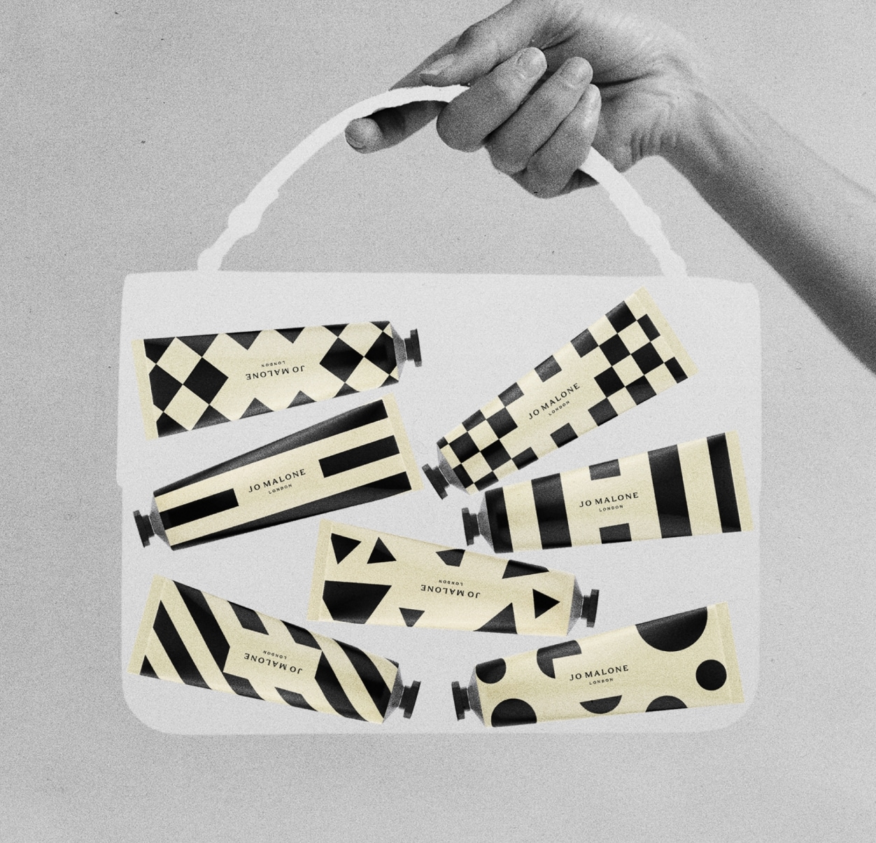 Image noire, blanche et crème d’un sac moyen transparent tenu par une main, contenant sept crèmes pour les mains à motifs dans des tubes.